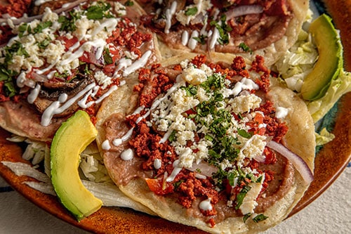 Los tacos se sirven con diversos ingredientes, como tocino, chorizo ​​y picadillo. Los acompañamientos incluyen frijoles refritos, huevo y pico de gallo.
